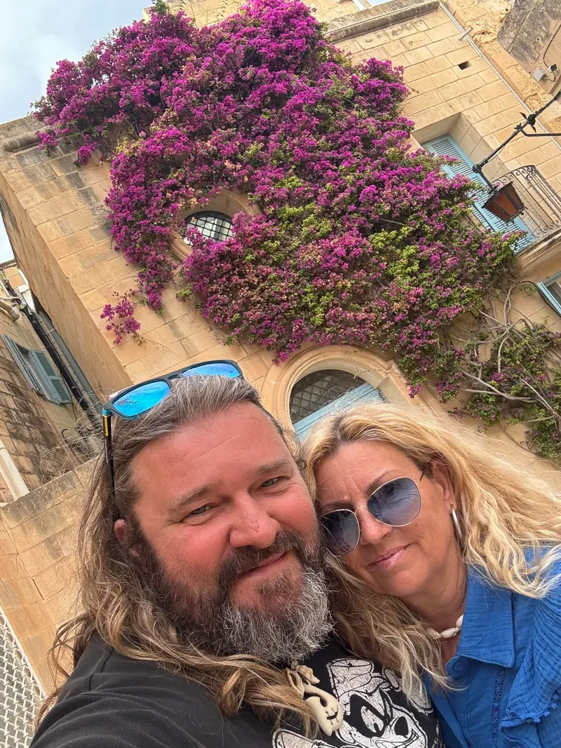 George és Mariann közös fotója egy virágzó bougainvillea előtt
