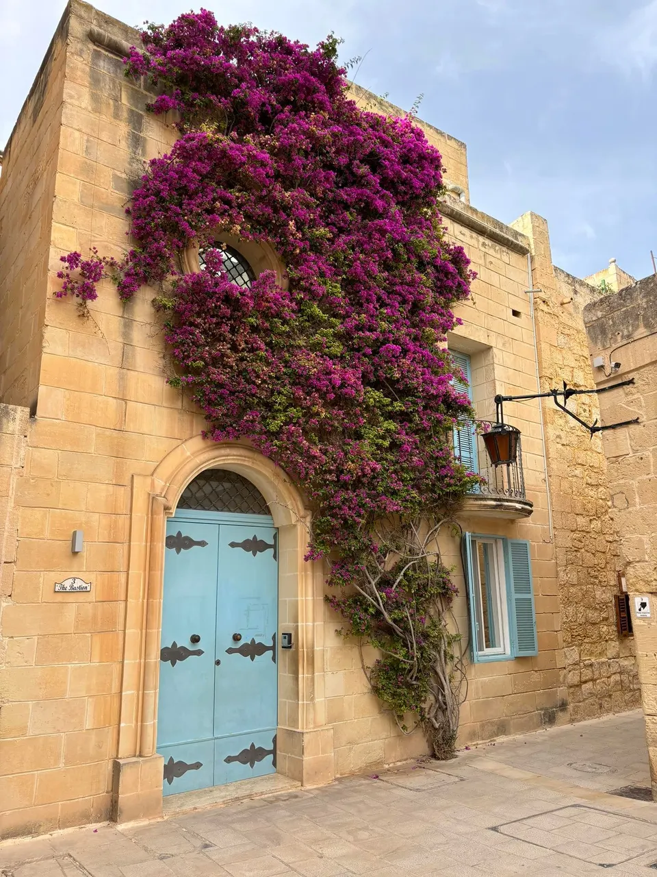 Bougainvilleával befutott mészkőház kék kapuval Mdina egyik csendes utcáján